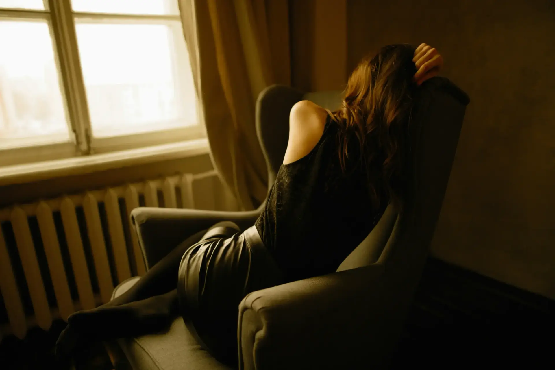 Dark image of teen with PMDD and ADHD, curled up on the couch