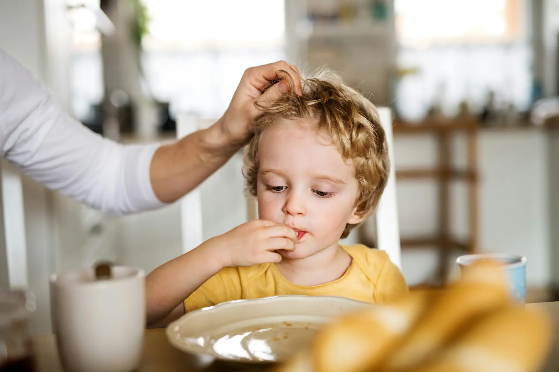 Fussy ASD child tentatively explores crumbs on a plate