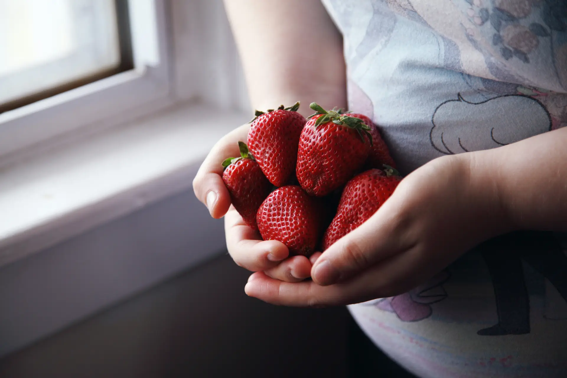 ADHD child holds handful of strawberries, which are high in vitamin C