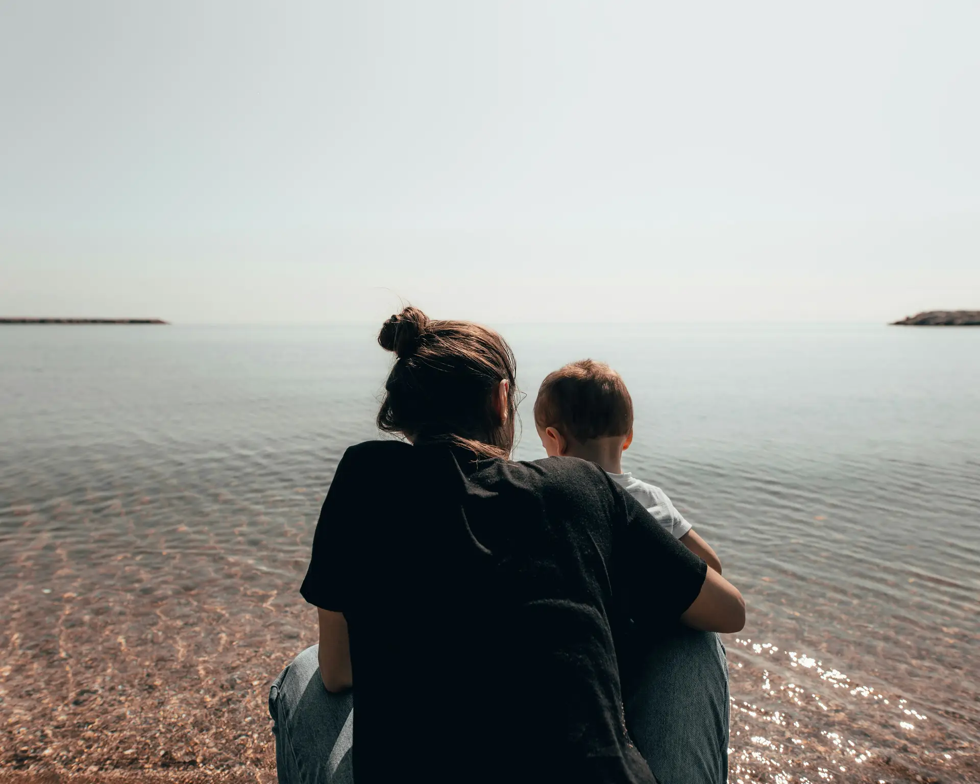 Mother and ASD son sitting at the beach having a hug