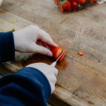 Hands of an ADHD child exploring food, cutting strawberries