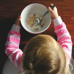 Toddler with ADHD eating a bowl of beige cereal with milk