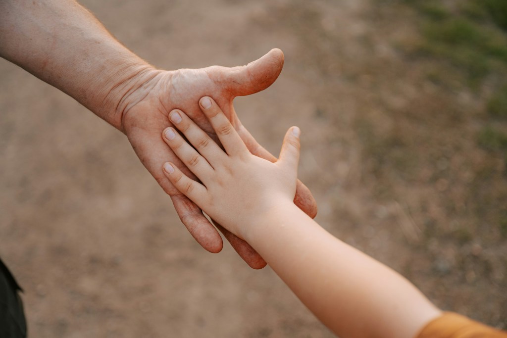 Disabled child reaching for the hand of a parent